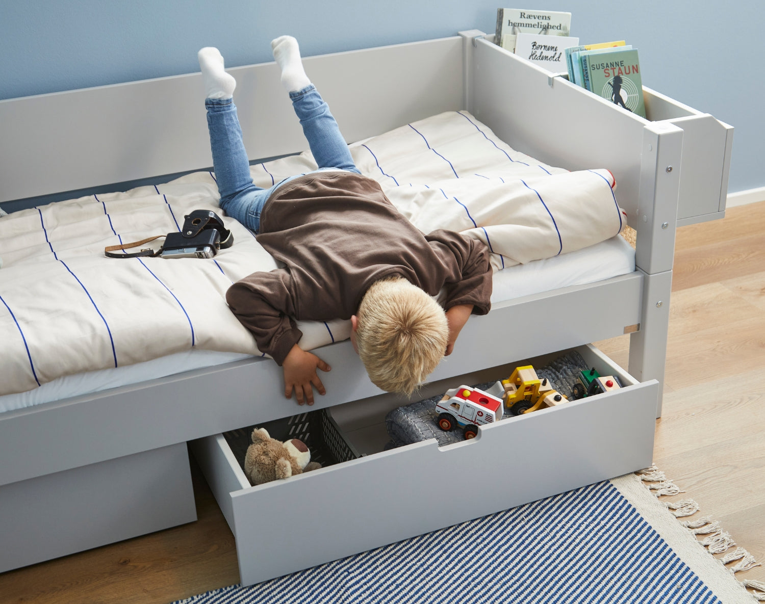 Sif børneseng med skuffer, barn kigger ned i legetøj