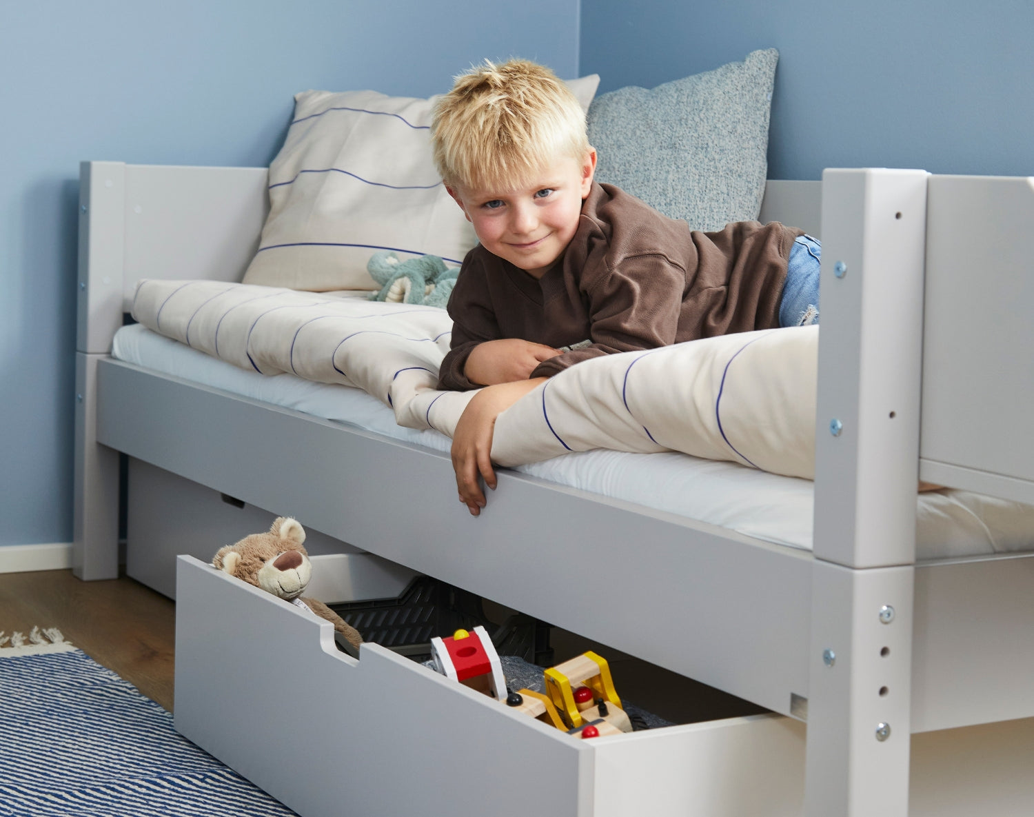 Glad dreng i Sif børneseng med udtræksskuffer og legetøj